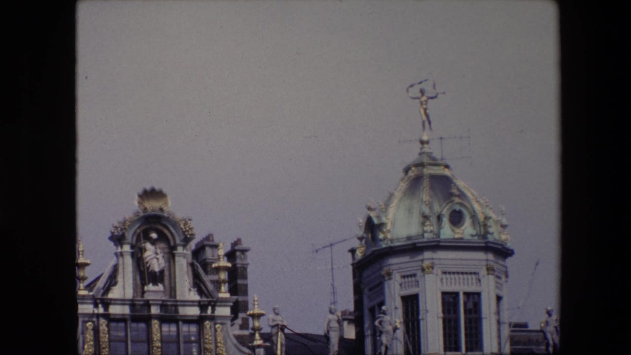Closer rooftop view with sculptural ornament, gilded trim, antennas, and a domed tower.