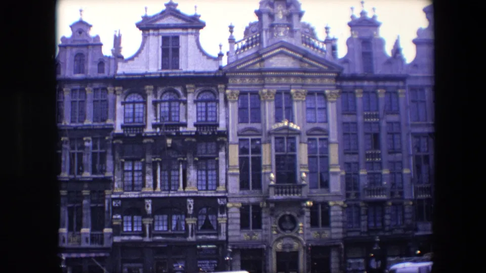1967 Brussels home-movie frame showing ornate historic multi-story facades with gables, balconies and decorative stonework.