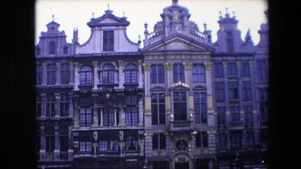 1967 Brussels frame with a steady view of richly decorated historic building fronts, tall windows and sculpted roofline details.