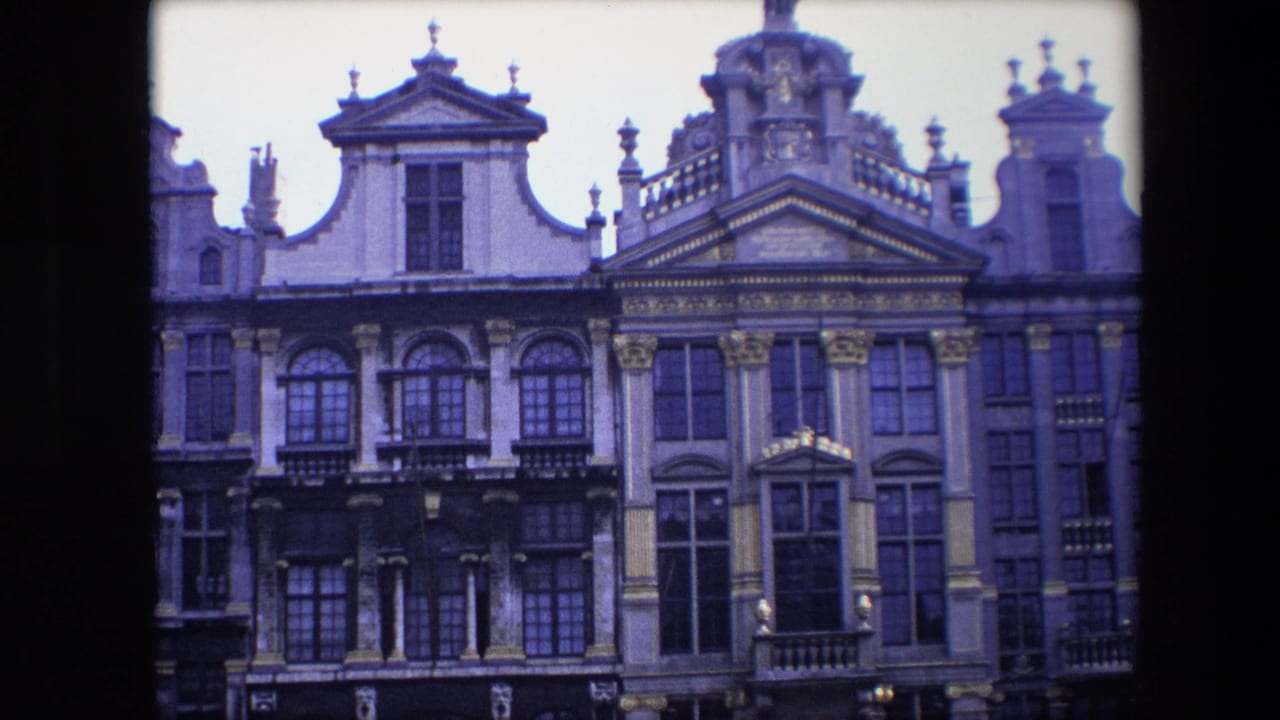 1967 Brussels home-movie frame showing ornate historic facades with arched windows, gilded trim, sculpted pediments, and upper roof decoration.