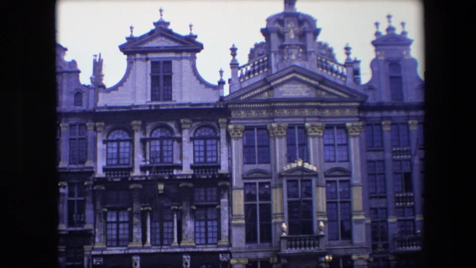 1967 Brussels home-movie frame showing ornate historic facades with arched windows, gilded trim, sculpted pediments, and upper roof decoration.