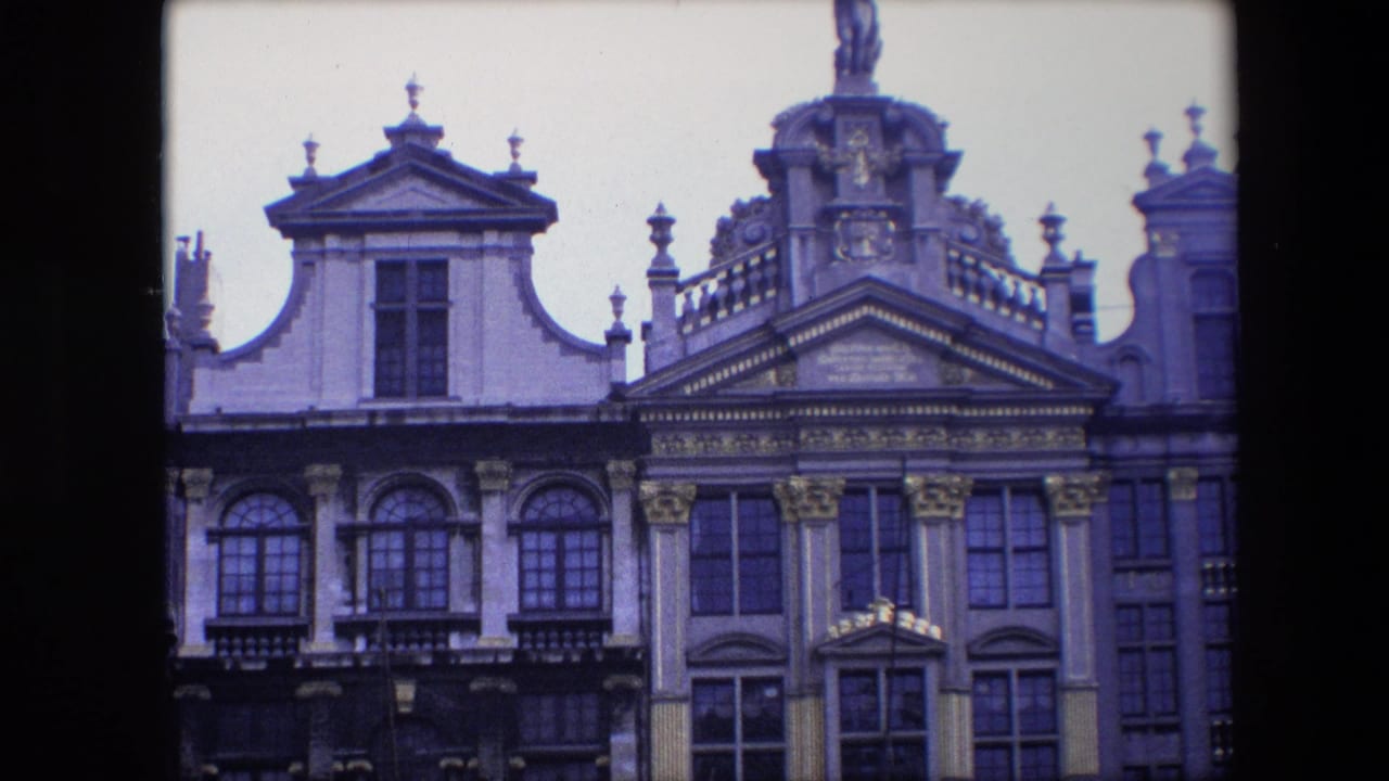 Historic building tops with pediments, arched windows, and a partial rooftop statue.