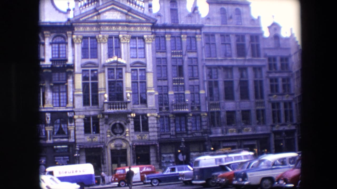 Ornate multi-story facades above a street with parked cars and a white lettered van.