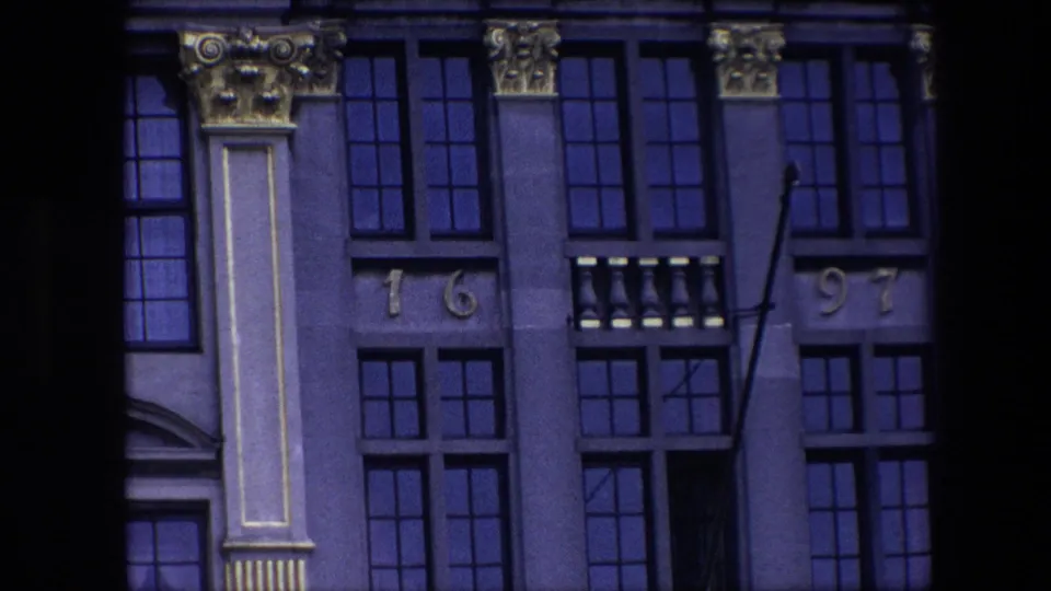 Visitor-shot 1967 Brussels frame of the ornate exterior, showing vertical columns, multi-pane windows, gilded capitals, and the split 1697 marking.