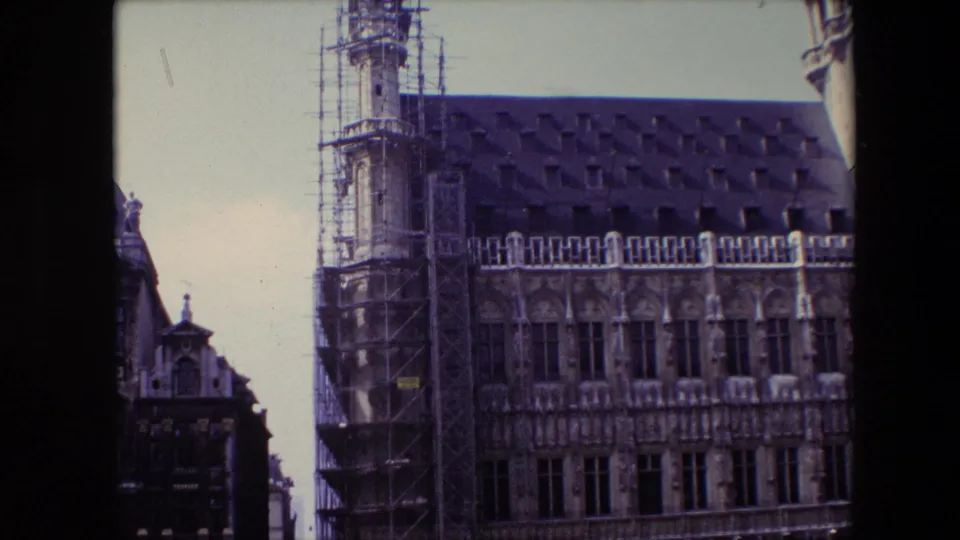1967 Brussels exterior view of an ornate Gothic-style historic building, likely the Brussels Town Hall, with scaffolding on the tower side and a steep dark roof.