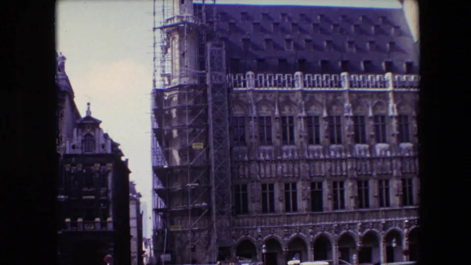 1967 Brussels exterior frame of a historic stone building with scaffolded side structure, rows of Gothic-style windows, arched lower arcade, and a dark tiled roof.