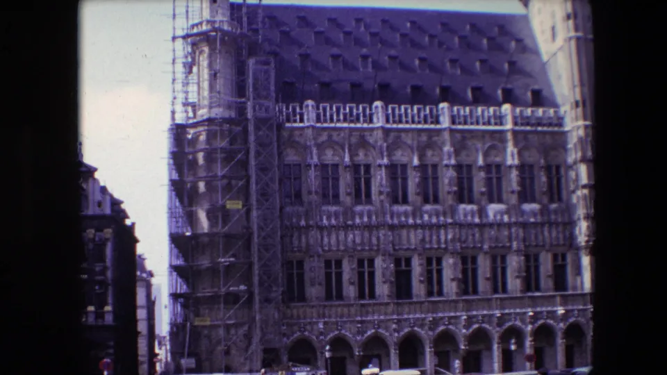 1967 Brussels street-level view of a historic landmark facade, with restoration scaffolding at the left and decorative stonework across multiple window bays.