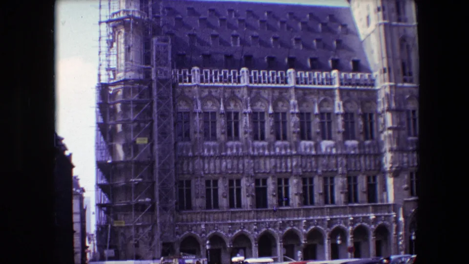 1967 Brussels footage shows a closer portion of the ornate facade, including scaffolding, rows of windows, arched lower openings, and the dark roofline.