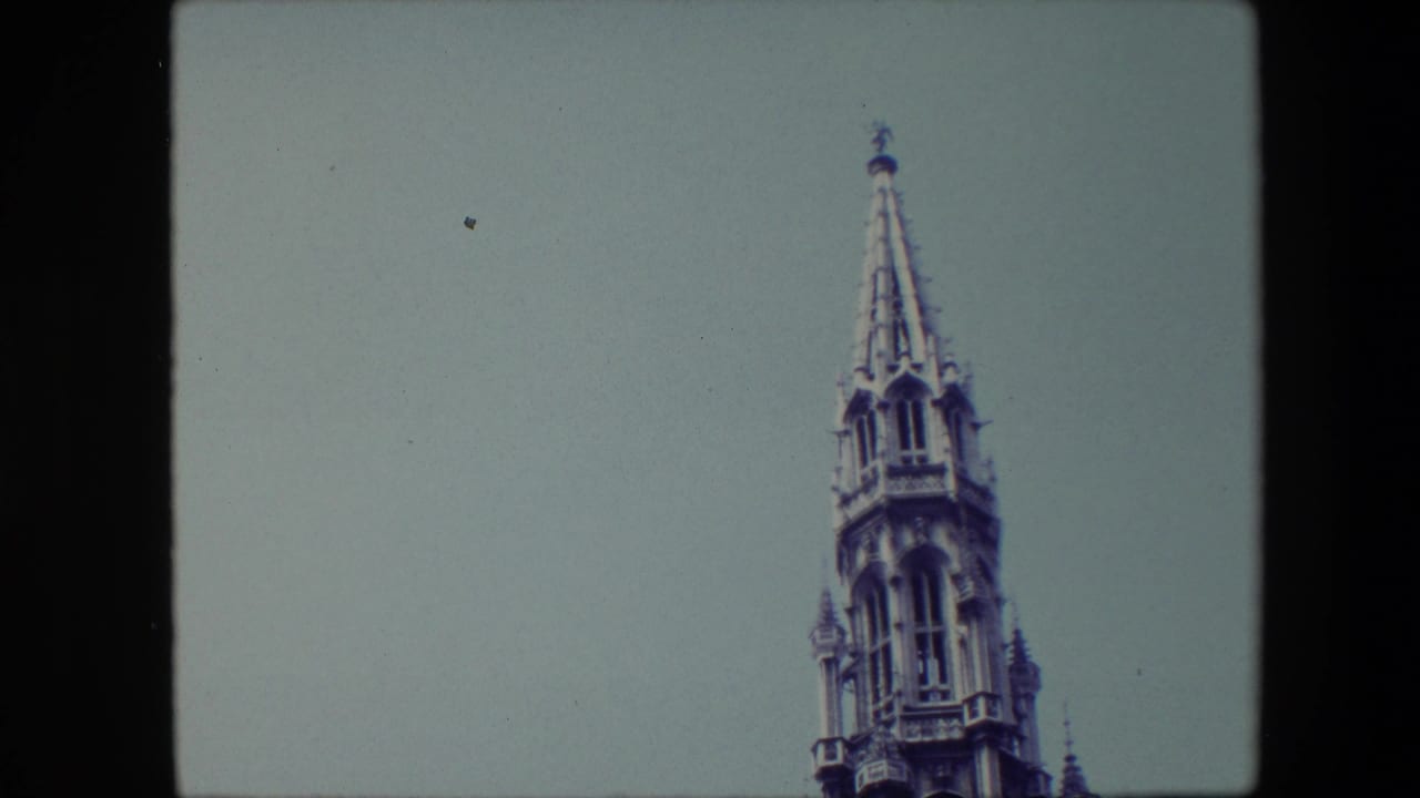 1967 Brussels frame with the spire shifted toward the right edge, emphasizing the pointed tower top and empty sky.