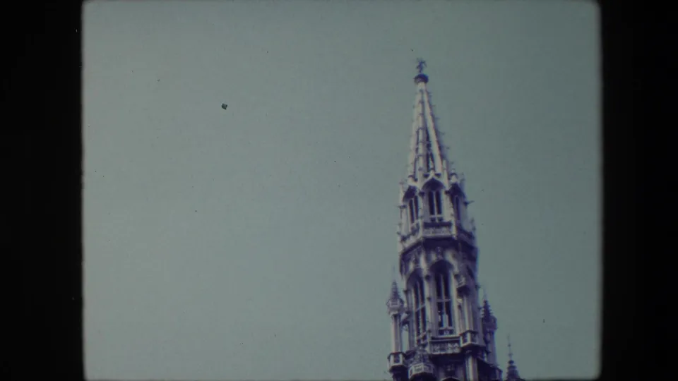 1967 Brussels frame with the spire shifted toward the right edge, emphasizing the pointed tower top and empty sky.
