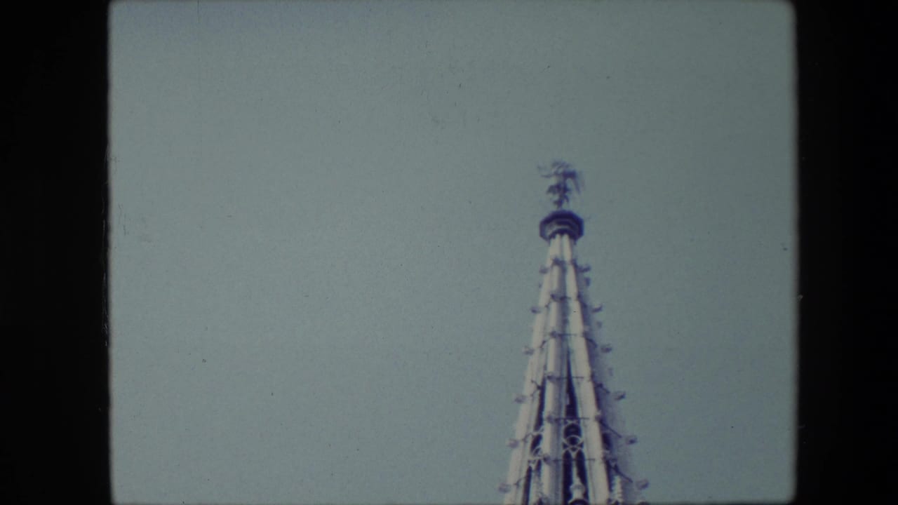 Gothic-style steeple top partly cropped beneath a pale blue sky.