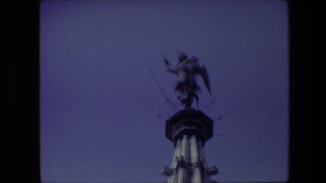 Winged statue on a monument seen against a darker blue sky.
