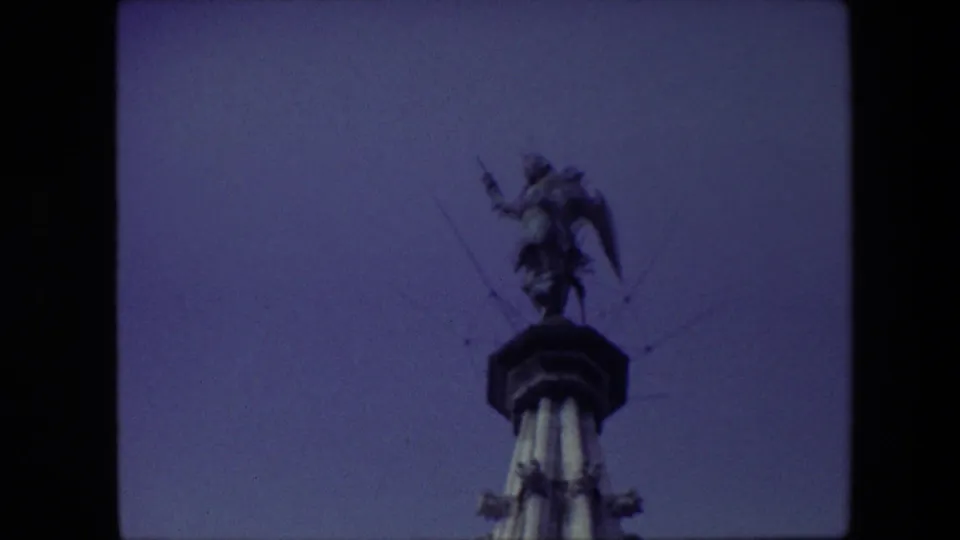 1967 Brussels 8mm frame with the winged statue and spear silhouetted more strongly against a darker blue-violet sky.