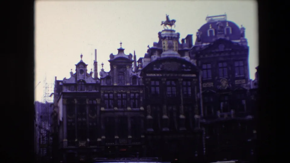 1967 Brussels 8mm frame showing a row of ornate historic buildings, including a central rooftop horse statue and mansard roof details.