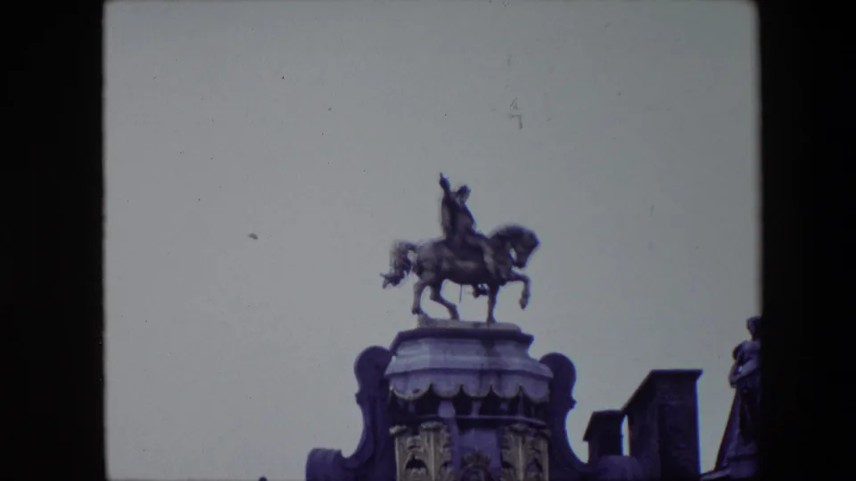 The final frame isolates the equestrian statue above the Brussels Grand Place facade, with surrounding roof edges and an overcast sky in soft 8mm color.