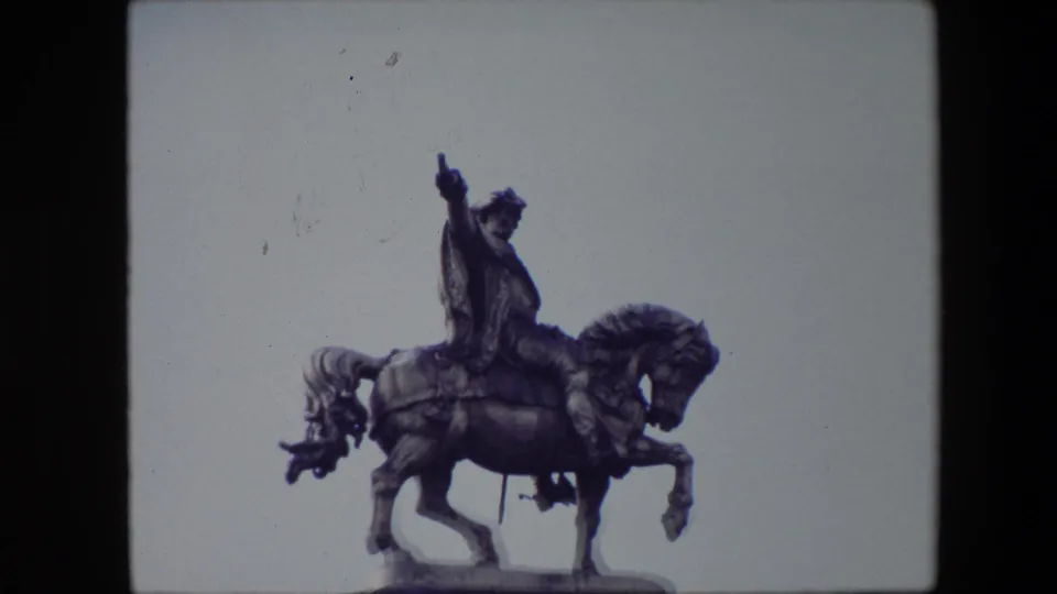 Final close 1967 Brussels frame of the bronze equestrian monument, with the rider and horse centered against the pale sky and visible film wear.