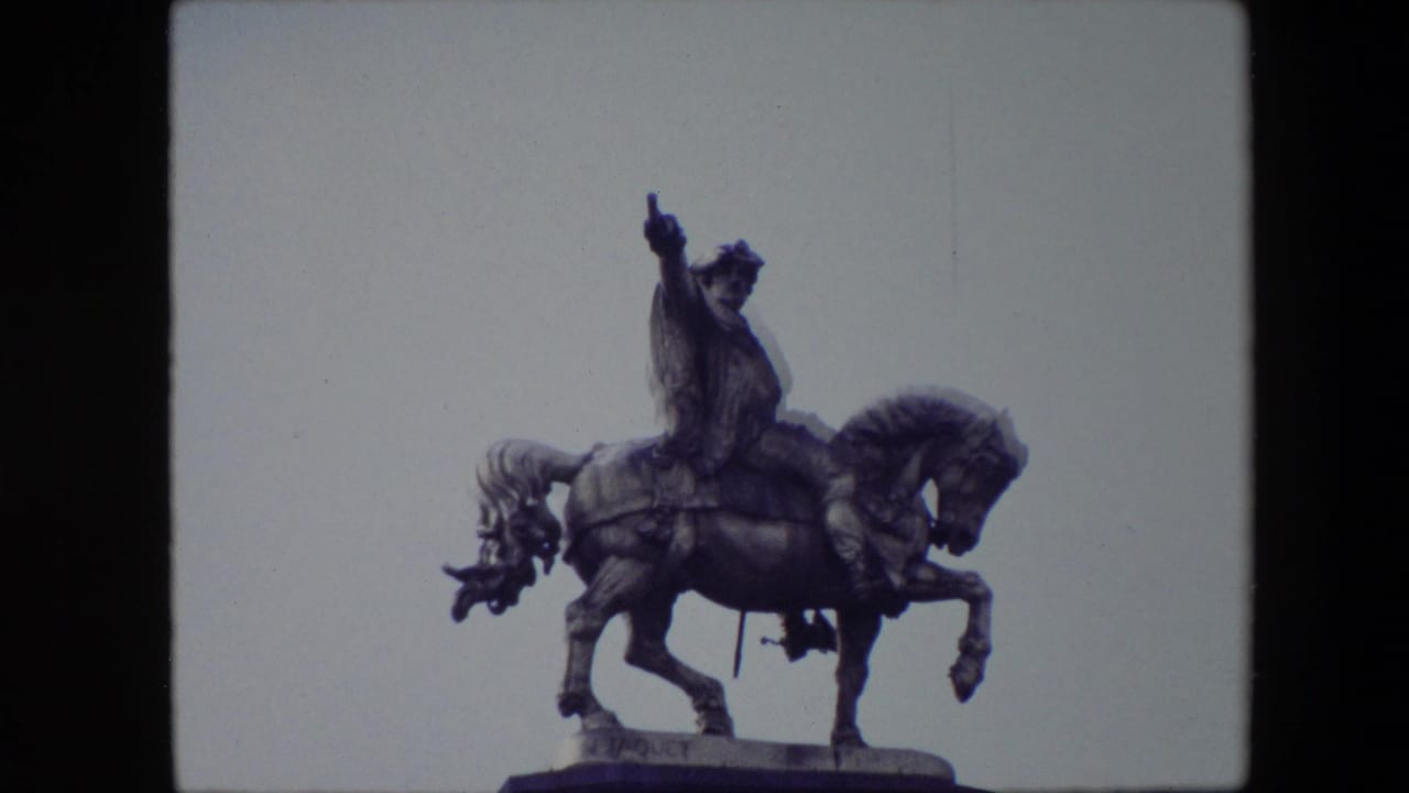 An equestrian monument in Brussels, Belgium, filmed in 1967 from a low visitor viewpoint against a pale sky with 8mm grain and soft color.
