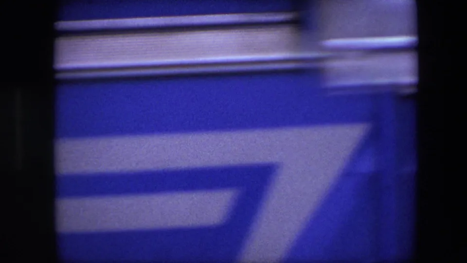 A blue and white blurred vehicle or street obstruction fills most of the frame, briefly obscuring the Brussels street scene.