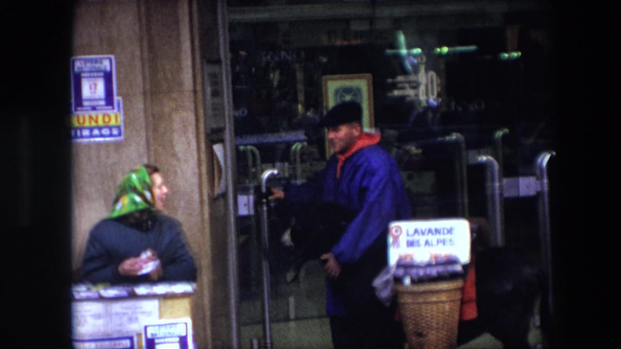 1967 Brussels street scene with a man in a blue coat and black hat holding a donkey beside baskets while speaking with a woman at a stand.