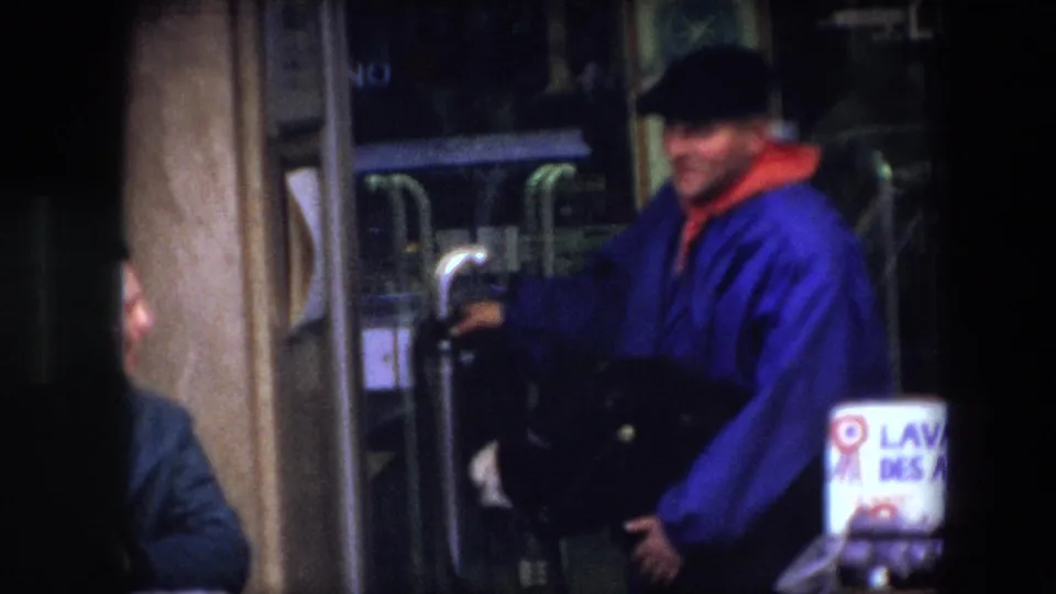 Closer 1967 Brussels frame showing the blue-coated vendor handling reins beside a donkey, with part of the woman and a labeled basket stand visible.