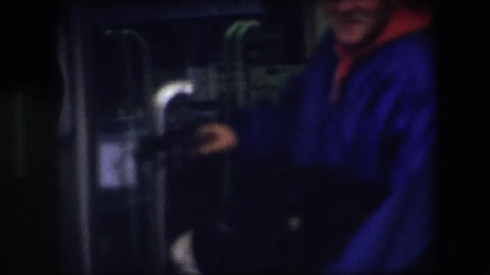Soft-focus 1967 Brussels close-up showing the vendor's blue coat, part of the donkey, glass doors, and a partially visible product sign on the sidewalk.