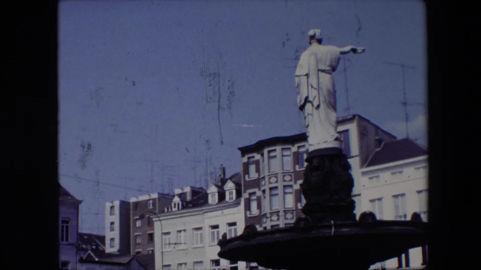 1967 Brussels frame with the statue higher in the composition, pointing across the square above pale and brick building facades.