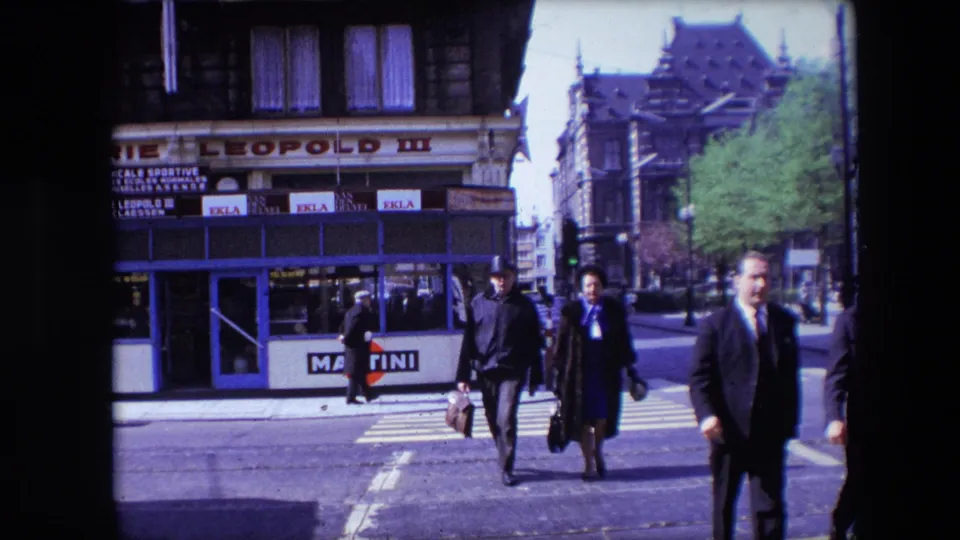 A 1967 Calais street view shows pedestrians crossing at a zebra crossing, with a suited man near the right edge and commercial signs in the background.