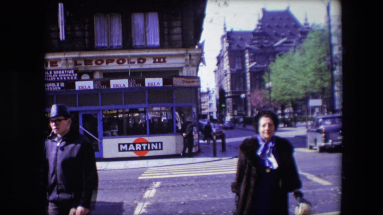 1967 Calais street corner with a woman in a dark coat and purple scarf crossing near Brasserie Leopold III as a man in a fedora passes in front of Martini advertising.