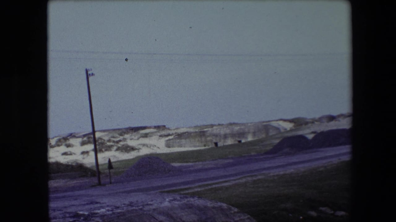 Roadside winter landscape with snowbanks, a utility pole, and low concrete structure.