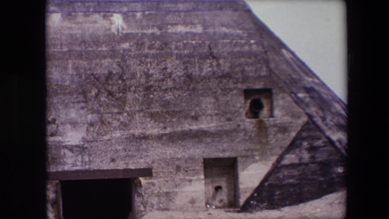 Closer view of bunker wall with square opening and dark entrance at the lower left.