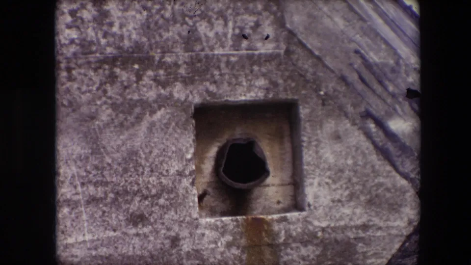 Tight 1967 Calais close-up of a square concrete bunker opening, showing a dark cylindrical pipe-like element, stained wall surface, and the sloped structure along the right edge.