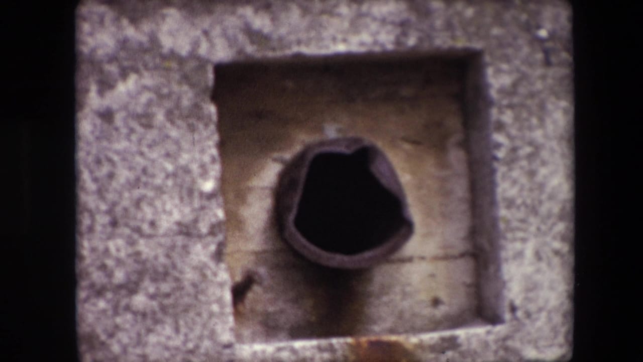 Tighter close-up of a rough concrete recess with a dark round opening.