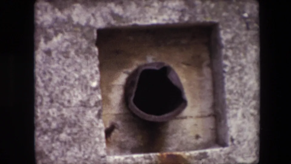 1967 Calais frame with a closer view of the bunker-like concrete recess and dark circular vent or pipe set into stained masonry.