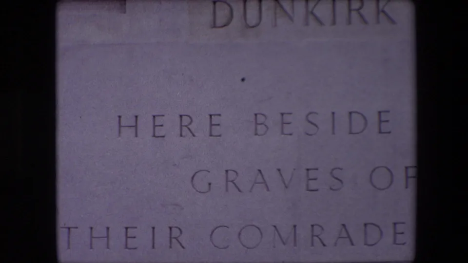 Close-up 1967 8mm view of a pale Dunkirk memorial inscription, with partial text reading “HERE BESIDE” and “GRAVES OF” visible across the stone.