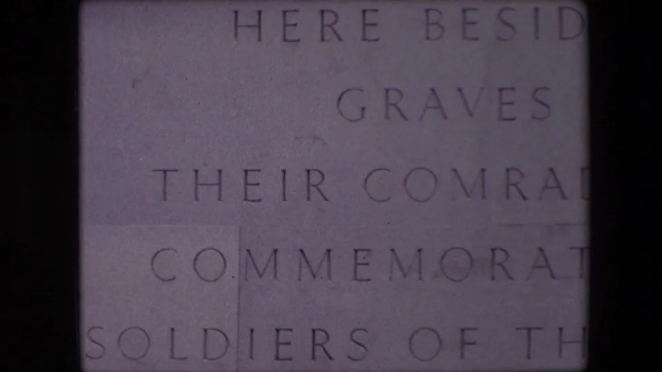 Close 1967 8mm view in Calais of pale stone blocks engraved with partial English memorial text mentioning graves, comrades, and soldiers.