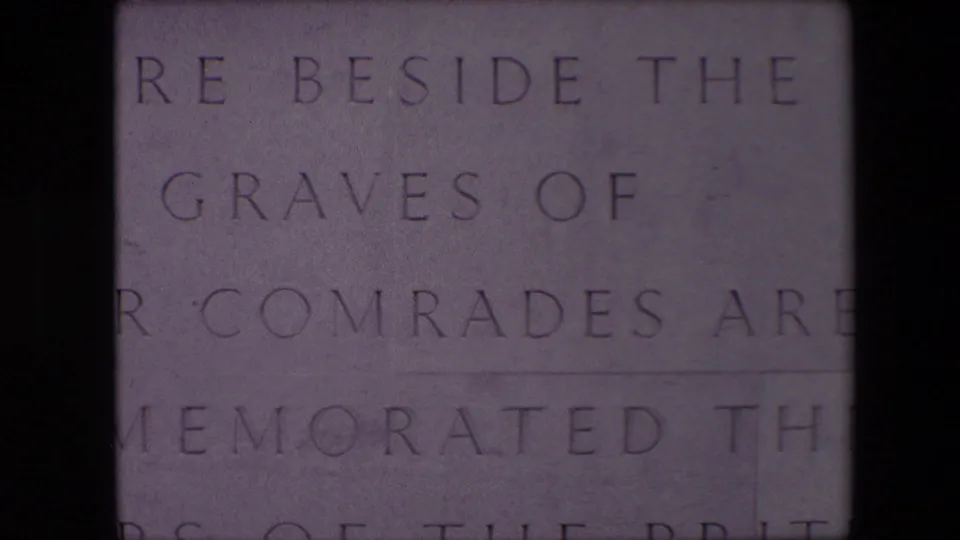 Lower close-up from the Calais memorial footage showing cropped engraved lines on pale stone, including references to graves and comrades.