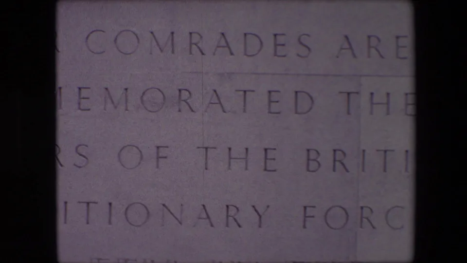 Close-up of the lower memorial inscription in Calais, with the words about comrades and the British Expeditionary Force partly visible across pale stone.