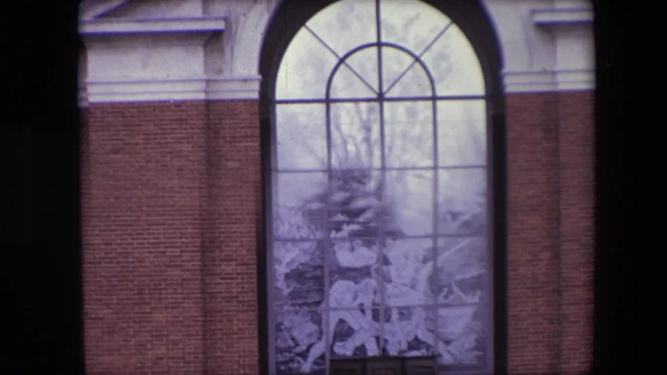 Close 1967 Calais view of the memorial's arched glass panel set between brick walls, with the decorative glass scene and window divisions filling most of the frame.