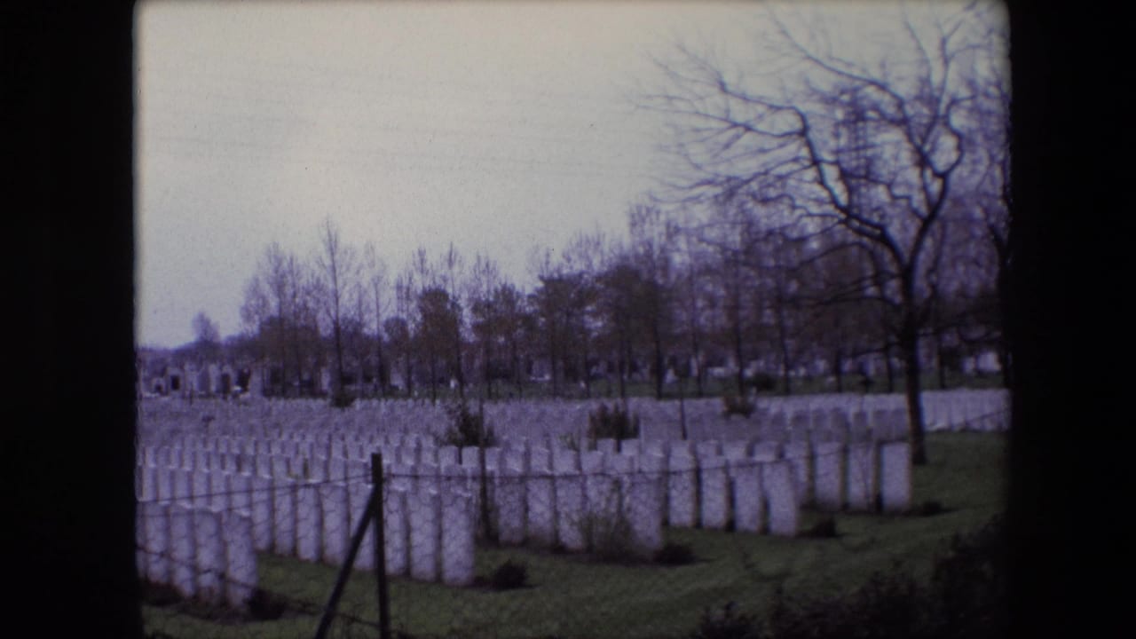 A 1967 Calais cemetery frame shows repeating rows of white headstones, winter-bare trees, grass, and a foreground fence line.