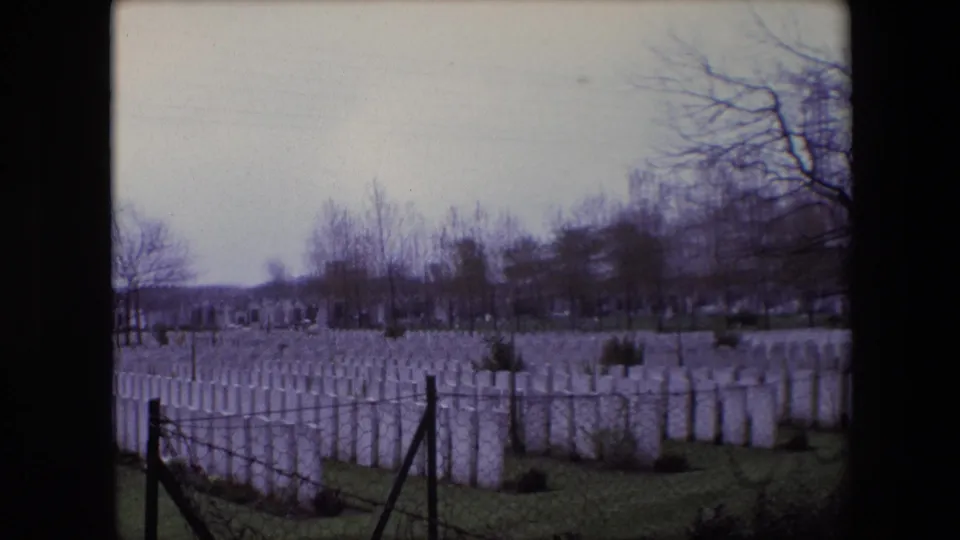The 1967 Calais footage widens slightly across the military cemetery, showing dense rows of white headstones, fence posts, shrubs, and leafless trees.