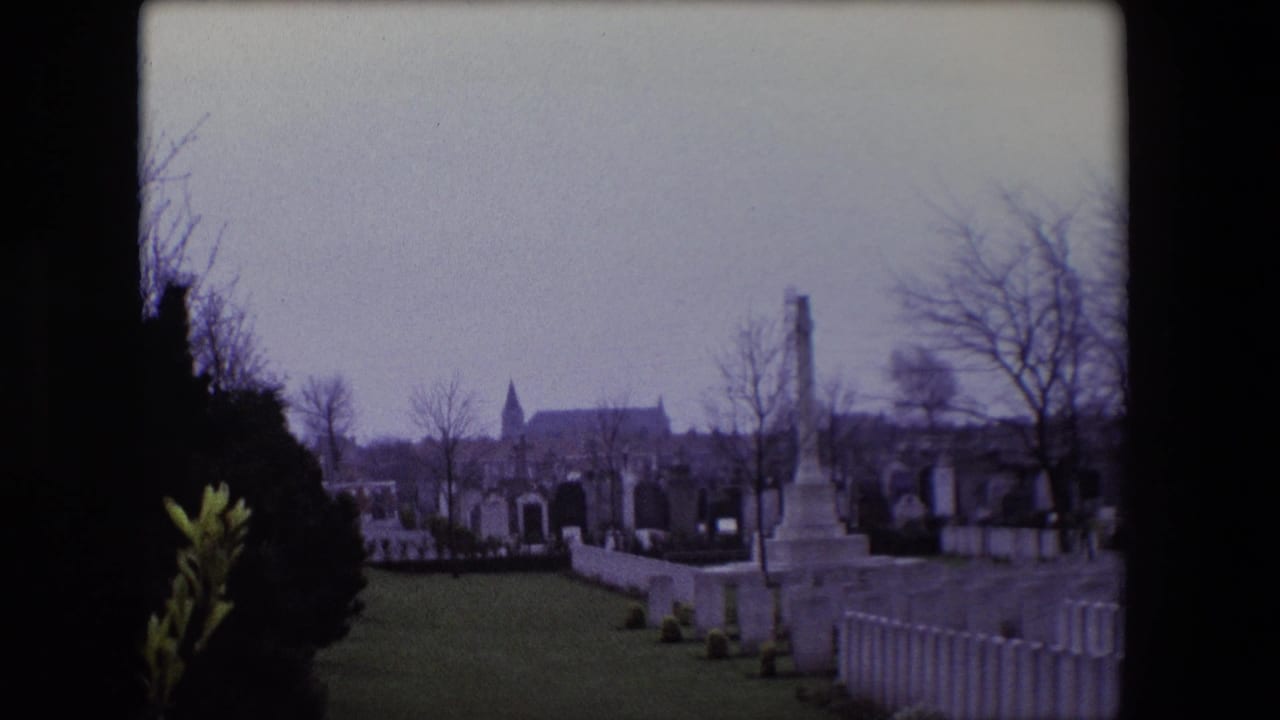 Calais, France cemetery scene from 1967 showing rows of white headstones, a distant church steeple, bare trees, and memorial structures.