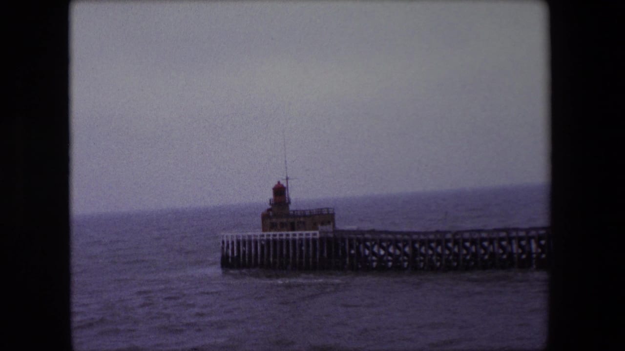 Pier lighthouse seen across choppy water with a dim horizon.