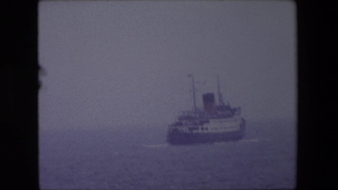 Large ship partly obscured by haze on calm water.