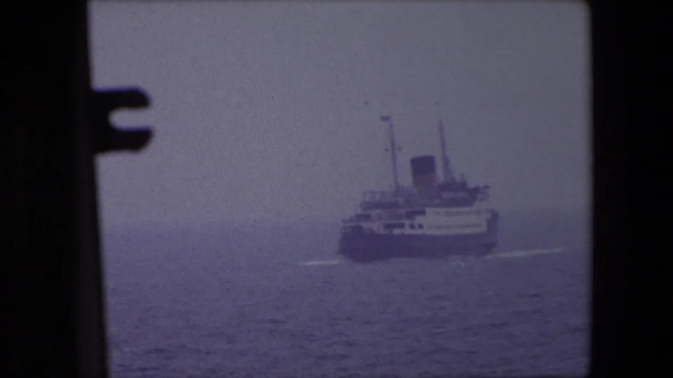 Distant passenger ship off Calais, France in 1967 appears through dark foreground frame edges on a hazy sea.
