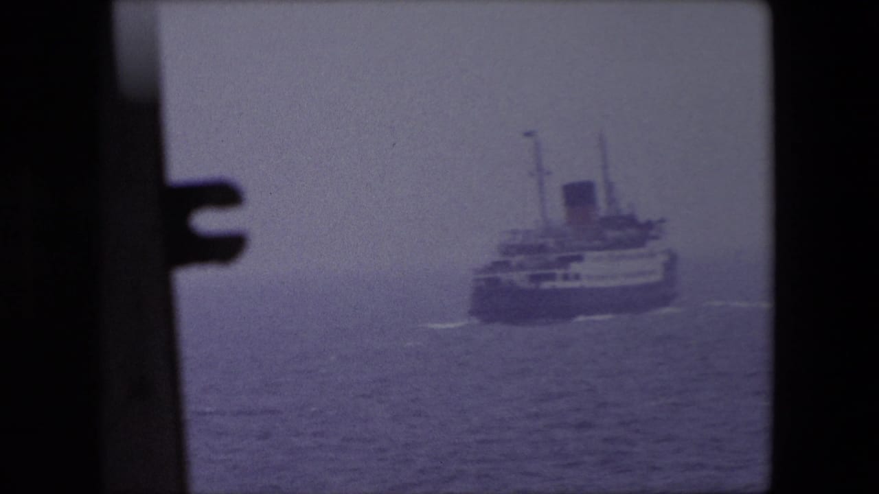 Passenger ship approaches at a slight angle across calm gray water.