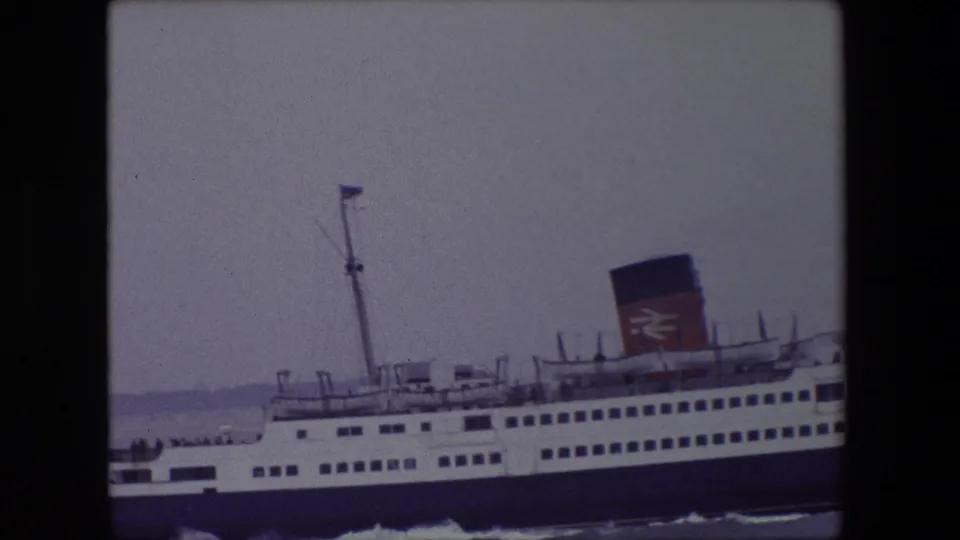 Closer 8mm frame from Calais in 1967 showing the ferry's forward passenger decks, mast, funnel marking, and waterline wake.