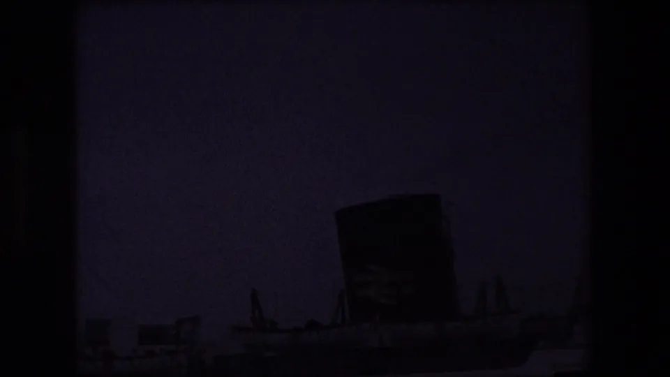 Underexposed 8mm frame from the Calais ferry sequence, with the funnel and deck structures faintly visible in the lower portion of the frame.
