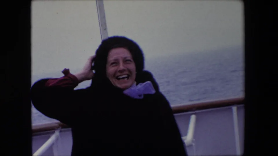 A closer 1967 Calais ship-deck frame shows the woman laughing as she holds her hair or hat in the wind, with the sea and white railing behind her.