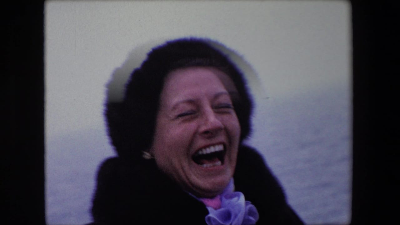 In 1967 Calais home-movie footage, a woman in a dark fur hat and coat laughs broadly on a boat with pale water behind her.