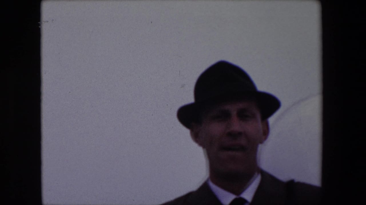 Adult man in fedora and suit looking toward the camera with his mouth slightly open.